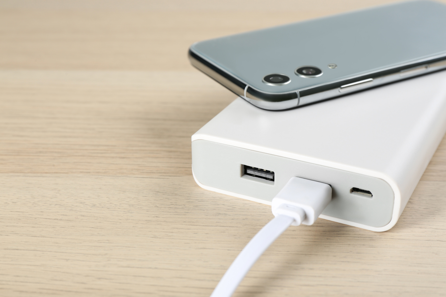 Mobile Phone and Portable Charger on Wooden Background, Closeup.